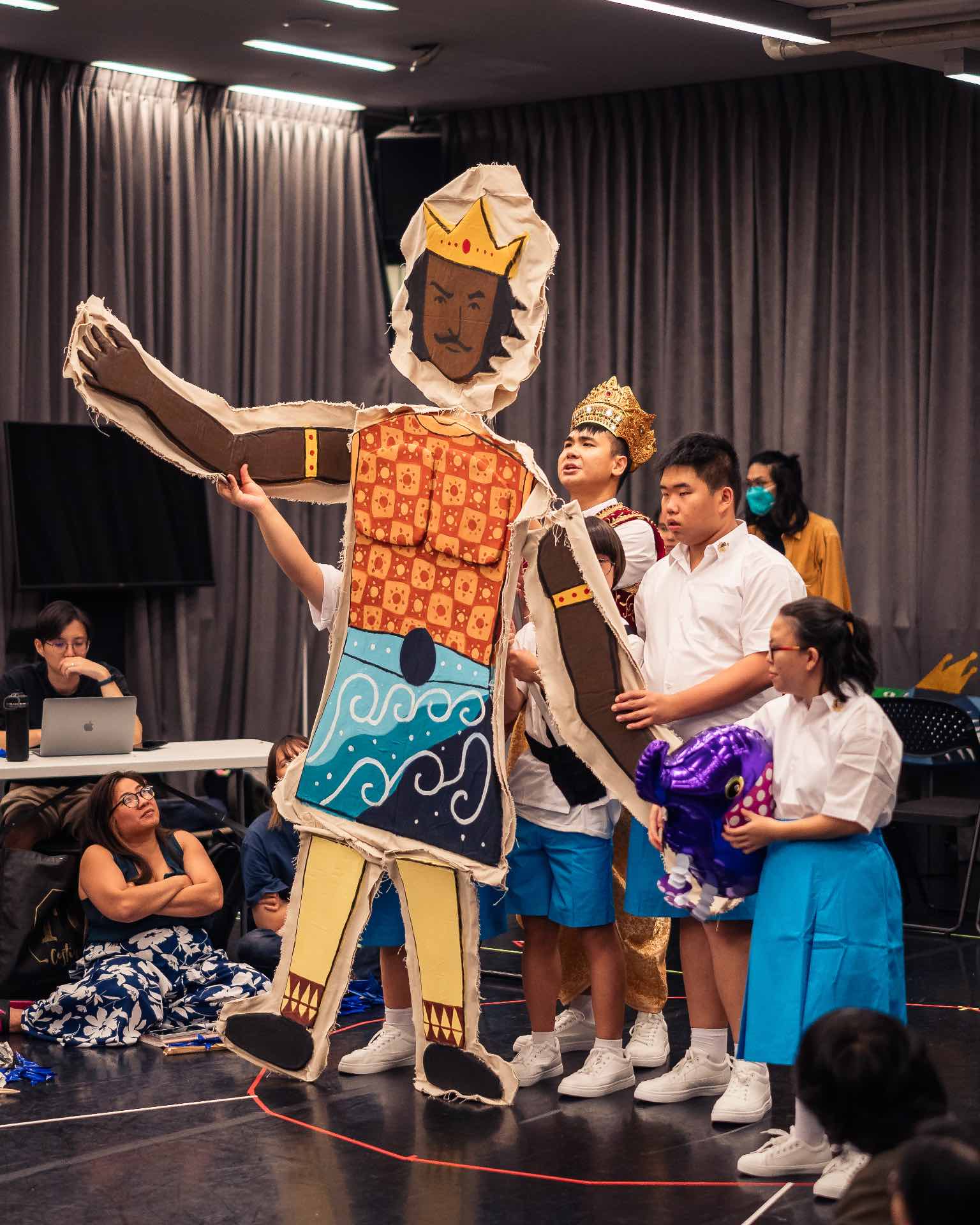 Actors and puppeteers work together to manoeuvre a large King puppet.